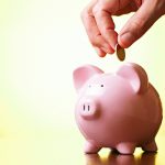 Man-paying-in-money-into-piggy-bank